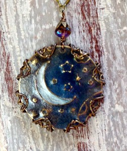 An indigo night with silvery moon and stars light up the night, wrapped in brass filigree.