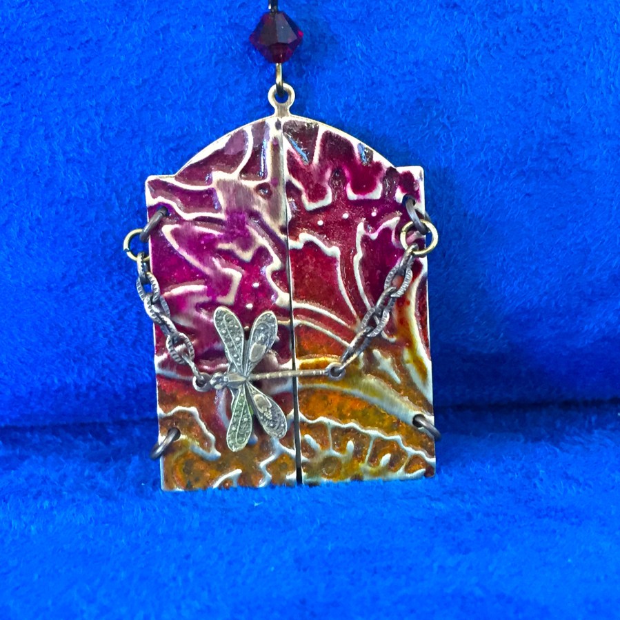 This golden firefly is winging his way among crimson hand tinted and embossed flowers.